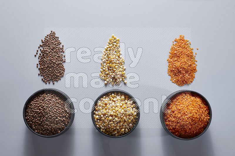 Legumes in pottery bowls on light grey background