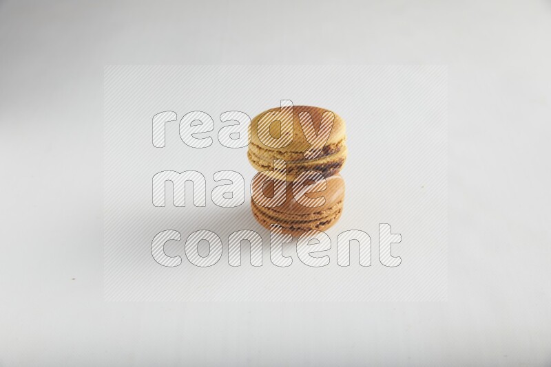 45º Shot of of two assorted Brown Irish Cream, and Yellow Crème Brulée macarons on white background