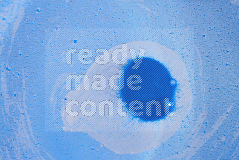 The image captures a dramatic splatter of blue paint over a blue backdrop