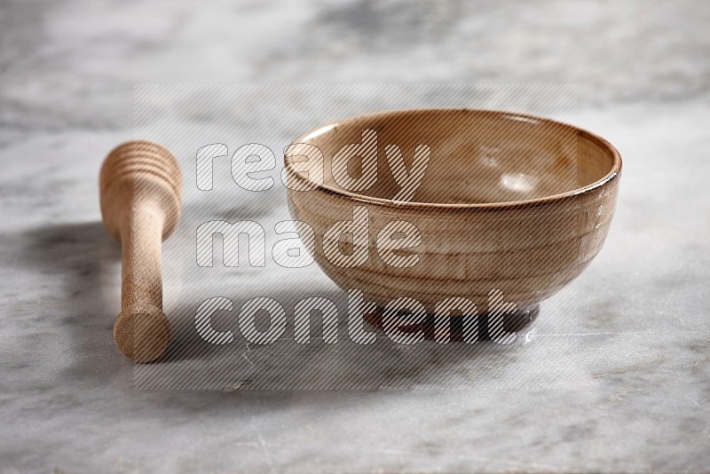 Beige Pottery bowl with wooden honey handle on the side with grey marble flooring, 15 degree angle