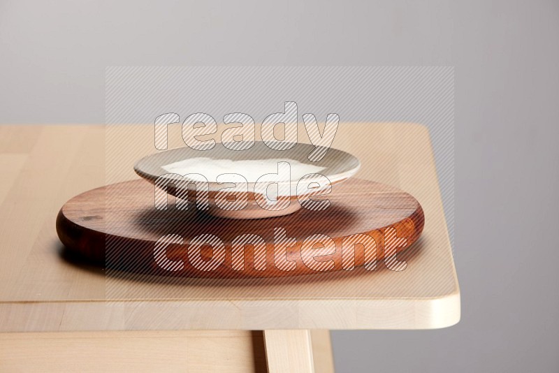 multi-colored pottery Plate placed on a dark colored wooden tray on the edge of wooden table