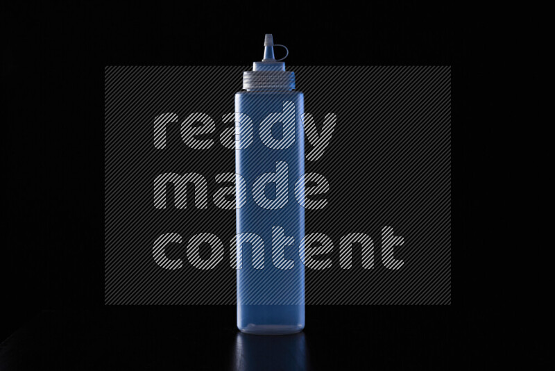 A squeeze bottle with colored rim light against black background