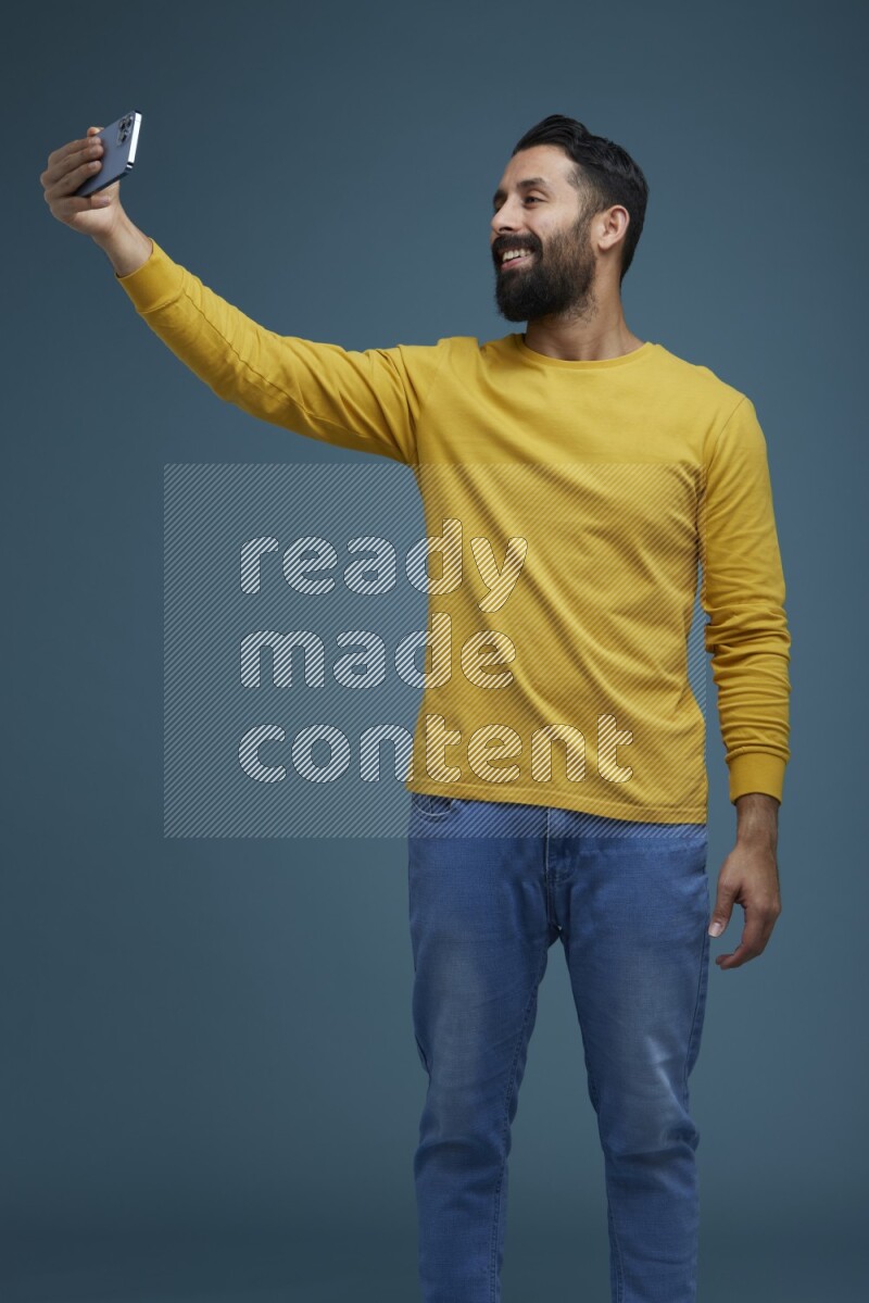 Man Taking a Selfie  in a blue background wearing a yellow shirt