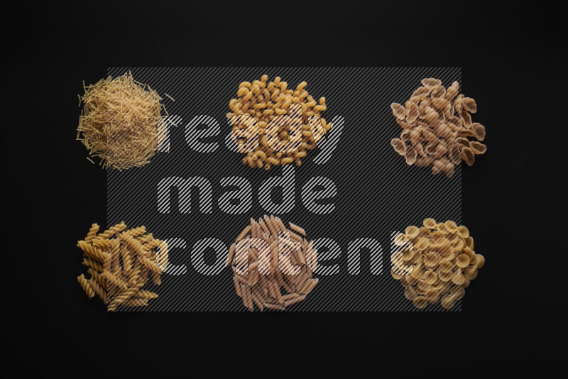Different pasta types in bunches on black background