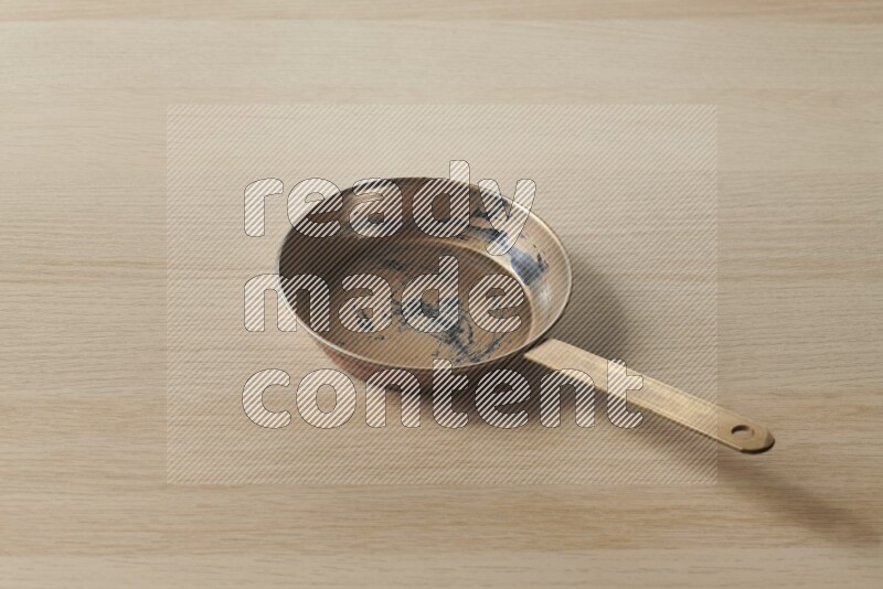 A small copper pan on light wooden background