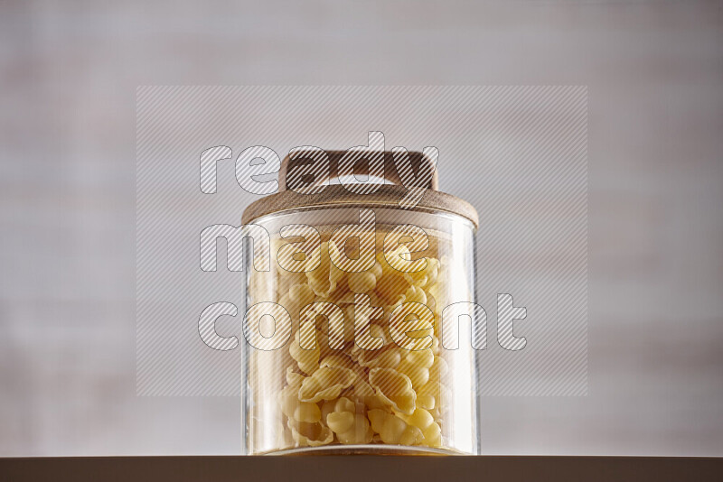 Raw pasta in glass jars on beige background