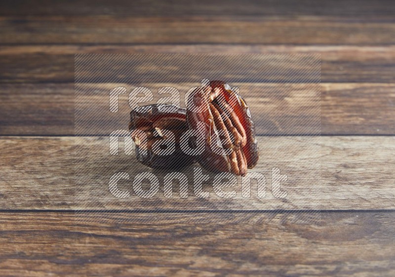 two pecan stuffed madjoul date on a wooden background