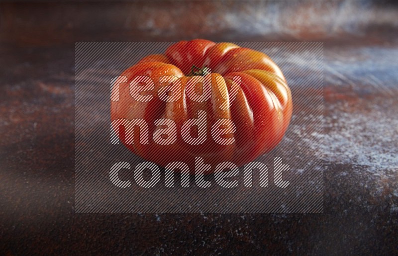 45 degree single heirloom tomato on  a textured reddish rustic metal background