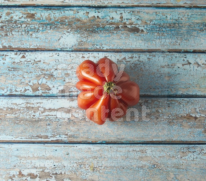 Single topview Heirloom tomato on a blue rustic wooden background