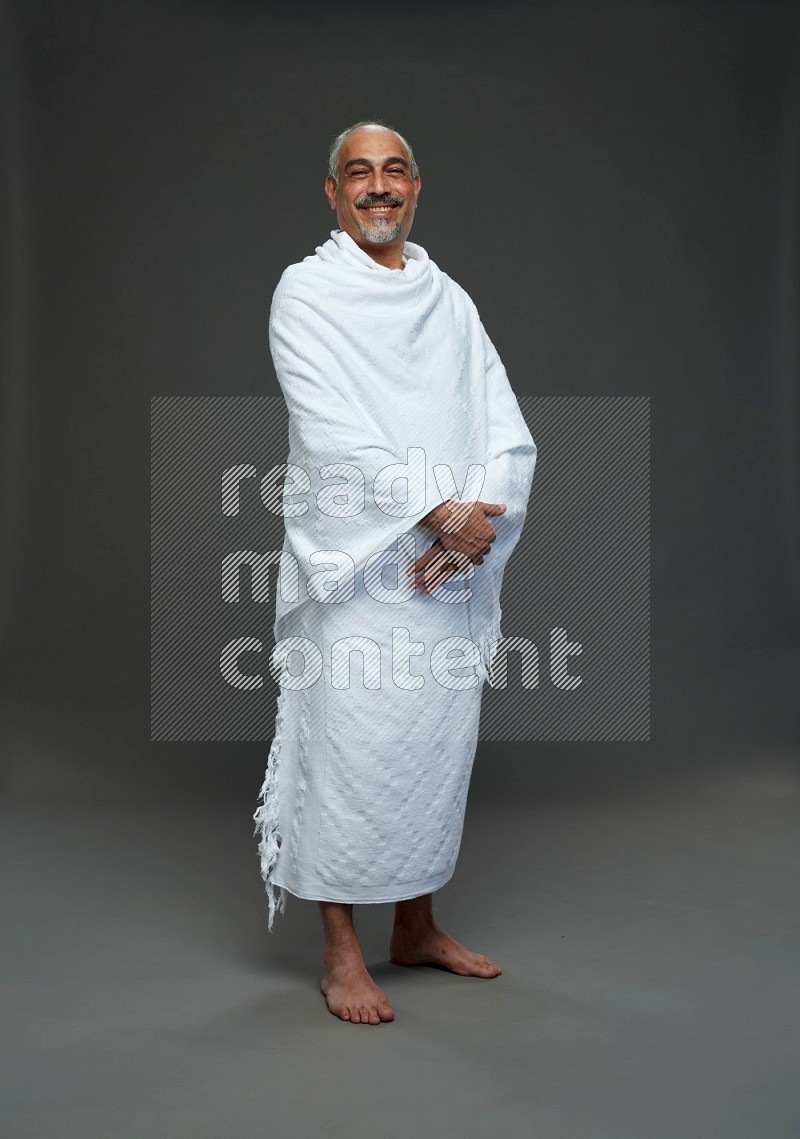 A man wearing Ehram Standing Interacting with the camera on gray background