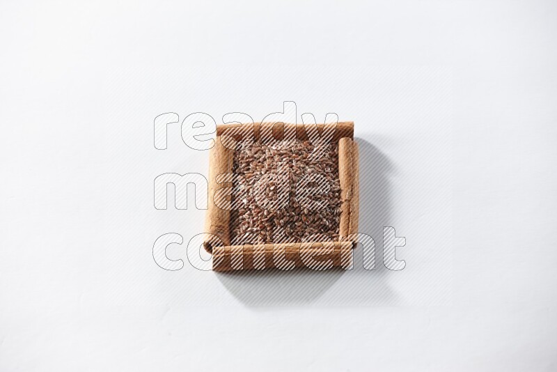 A single square of cinnamon sticks full of flaxseeds on white flooring