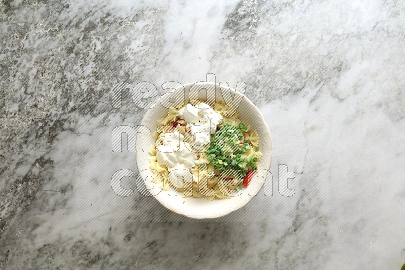 White bowl full of pasta on grey marble background