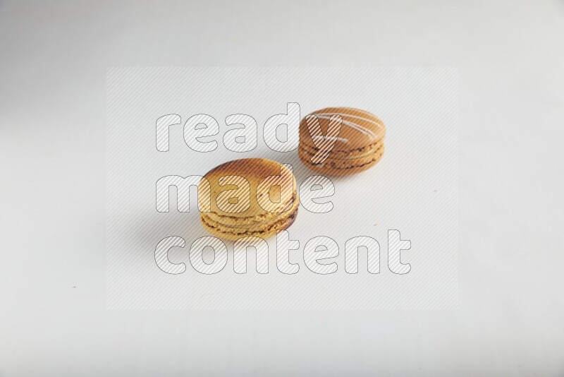 45º Shot of of two assorted Brown Irish Cream, and Yellow Crème Brulée macarons on white background