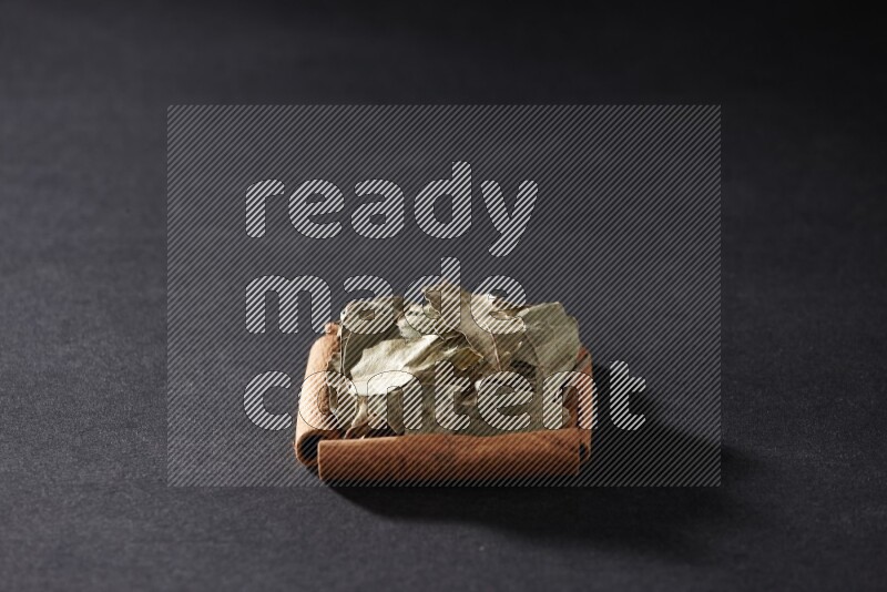 A single square of cinnamon sticks full of laurel bay on black flooring