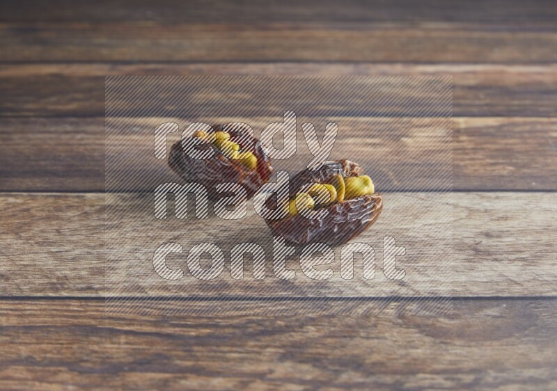 two pistachio stuffed madjoul date on a wooden background
