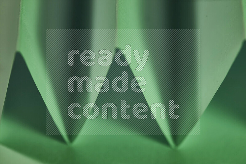 صورة مجردة مقربة تظهر طيات ورقية هندسية حادة بتدرجات اللون الأخضر