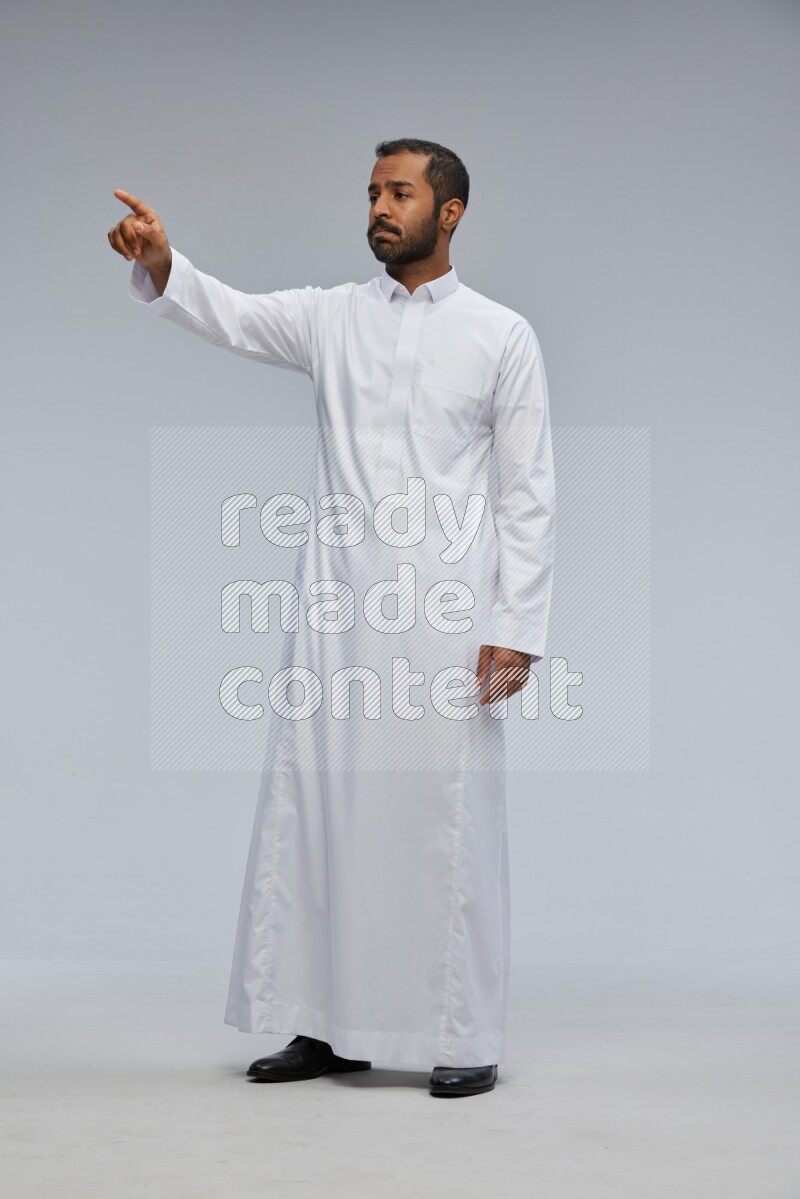 Saudi man Wearing Thob standing interacting with the camera on Gray background