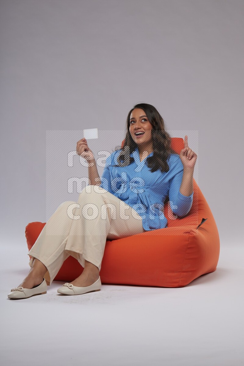 A woman sitting on an orange beanbag and holding ATM card