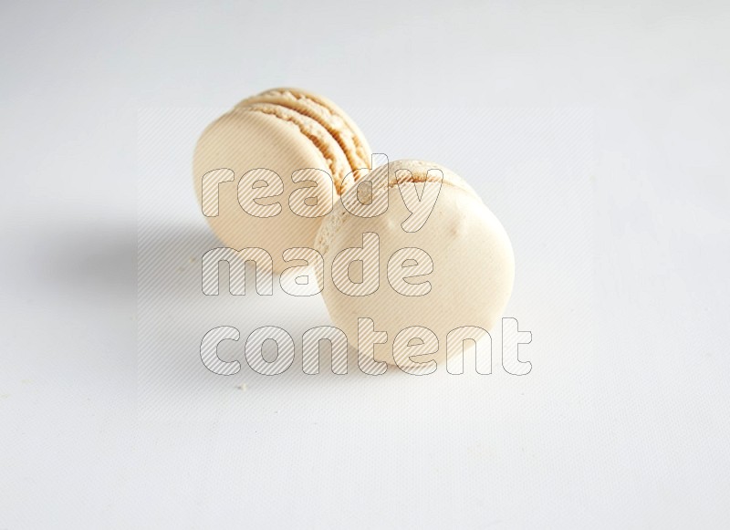 45º Shot of two White Caramel fleur de sel macarons on white background