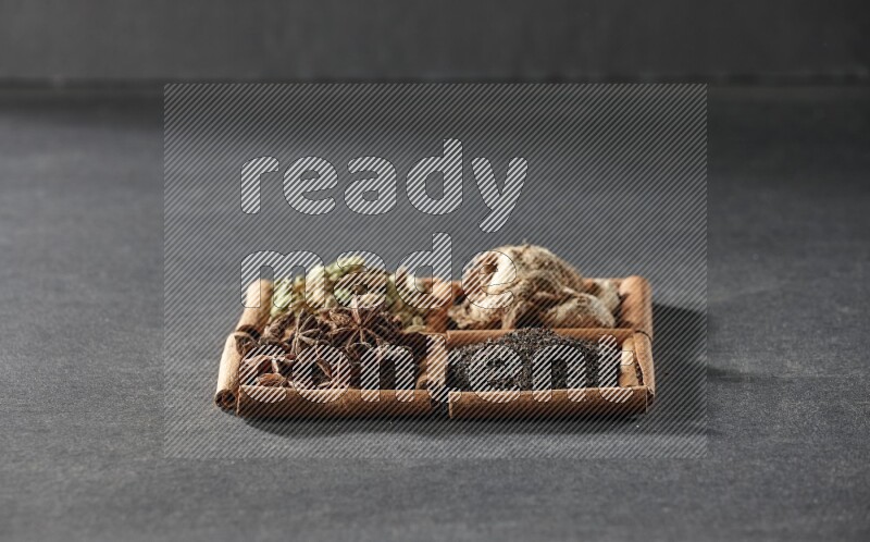 4 squares of cinnamon sticks full of tea, star anise, dried ginger and cardamom on black flooring
