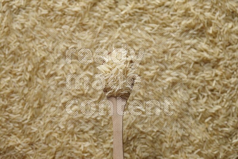 ملعقة خشبية مليئة بالأرز البسمتي علي خلفية من الأرز البسمتي