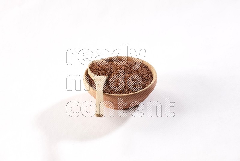 وعاء خشبي وملعقة خشبية كلاهما ممتلئان ببذور حب الرشاد علي خلفية بيضاء