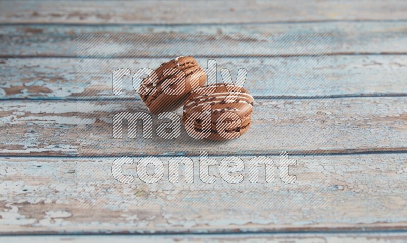 45º Shot of two Brown white  Chocolate Caramel macarons on light blue wooden background