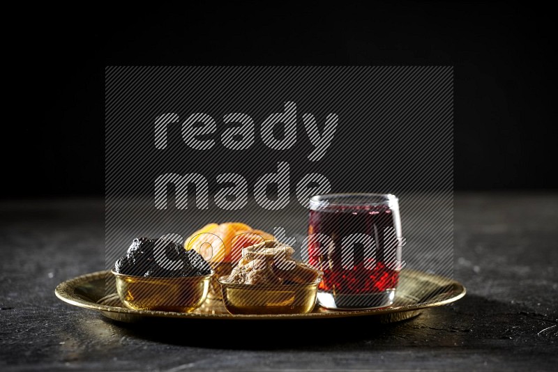 Dried fruits in metal bowls with Hibiscus on a tray in dark setup