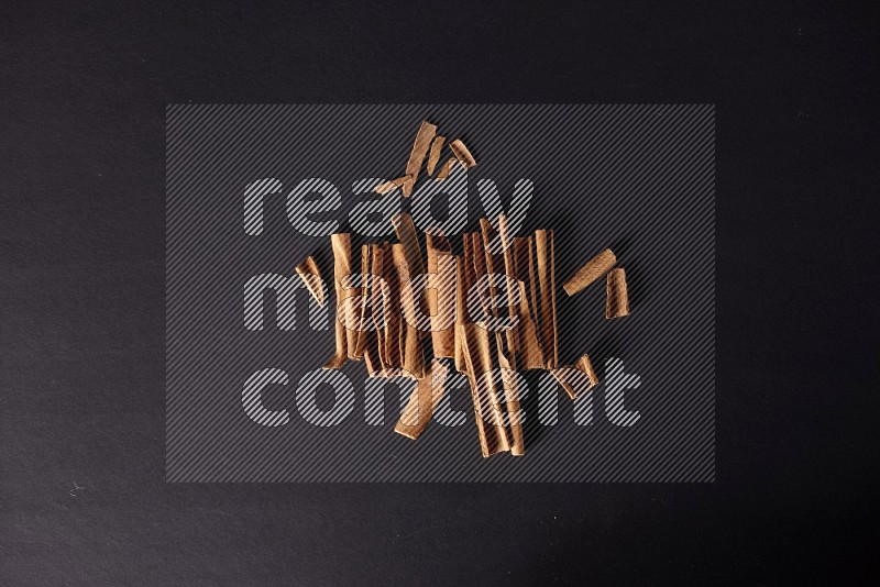 Cracked cinnamon sticks on a black background