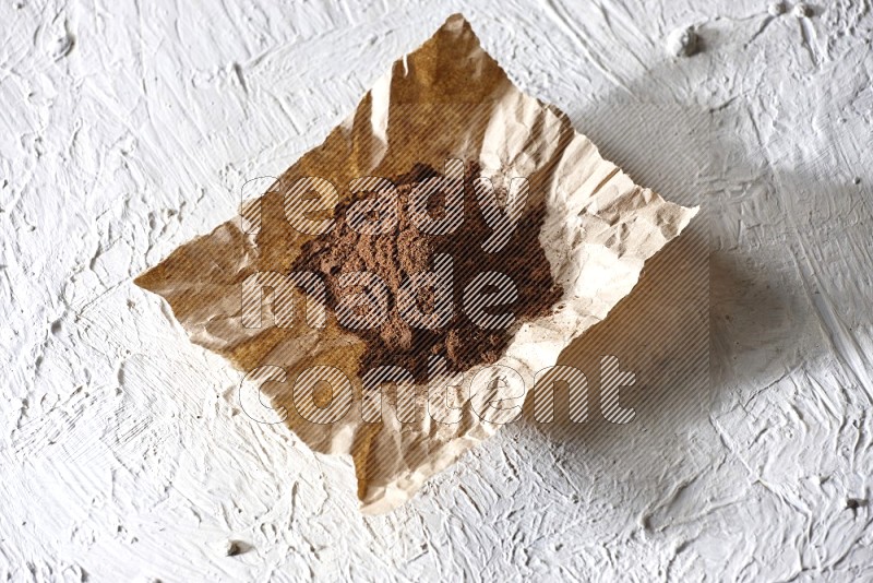 Cloves powder on crumpled piece of paper on a textured white flooring