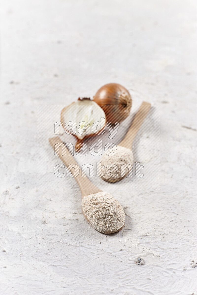 Two wooden spoons full of onion powder on white background