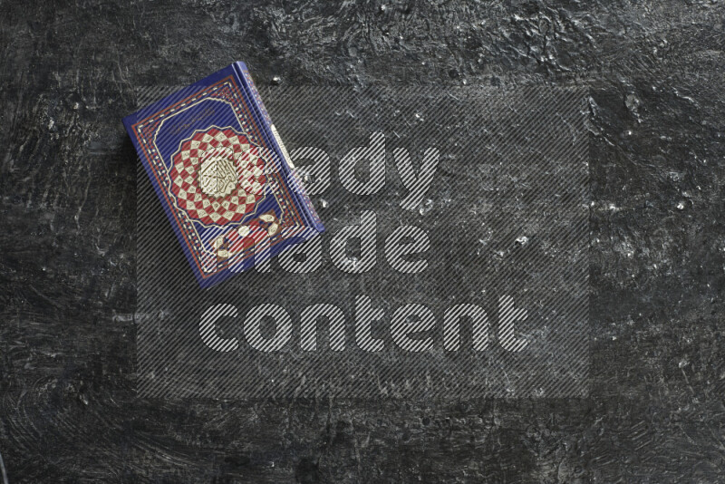 Quran with a prayer beads on textured black background