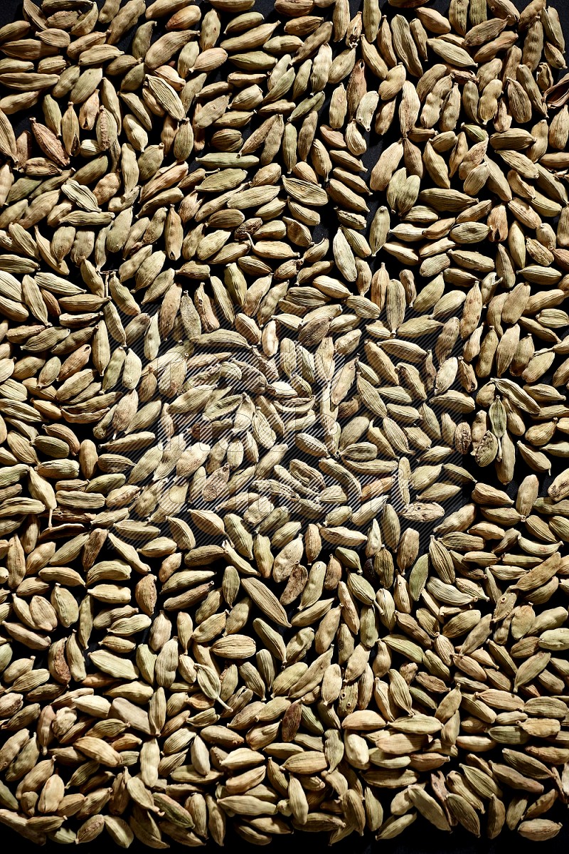 Cardamom seeds filling the frame on black flooring