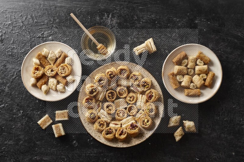 Oriental sweets in pottery plates with honey in a dark setup