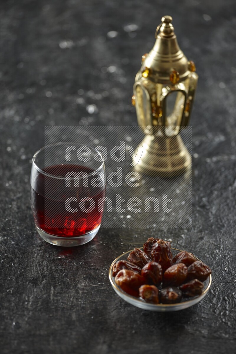A golden lantern with different drinks, dates, nuts, prayer beads and quran on textured black background