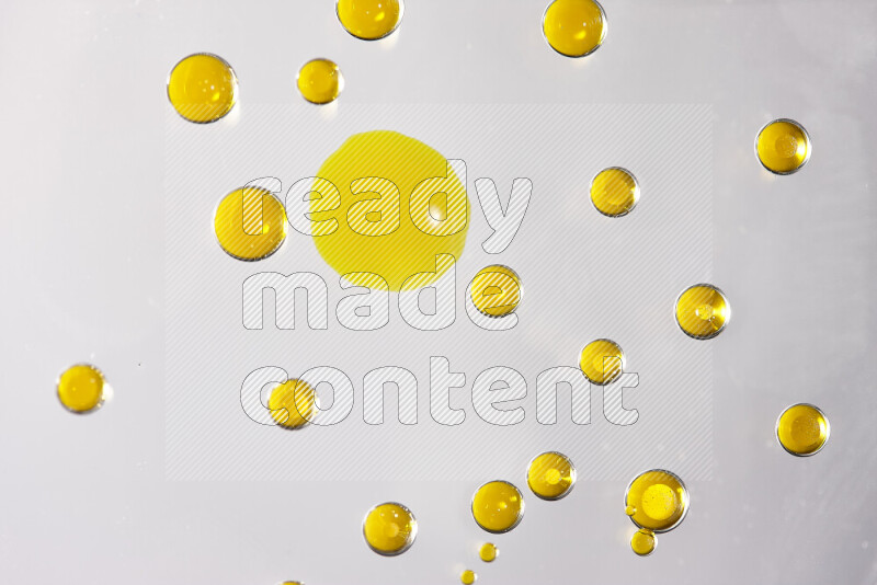 لقطات مقربة لقطرات ألوان مائية صفراء على سطح الزيت على خلفية بيضاء