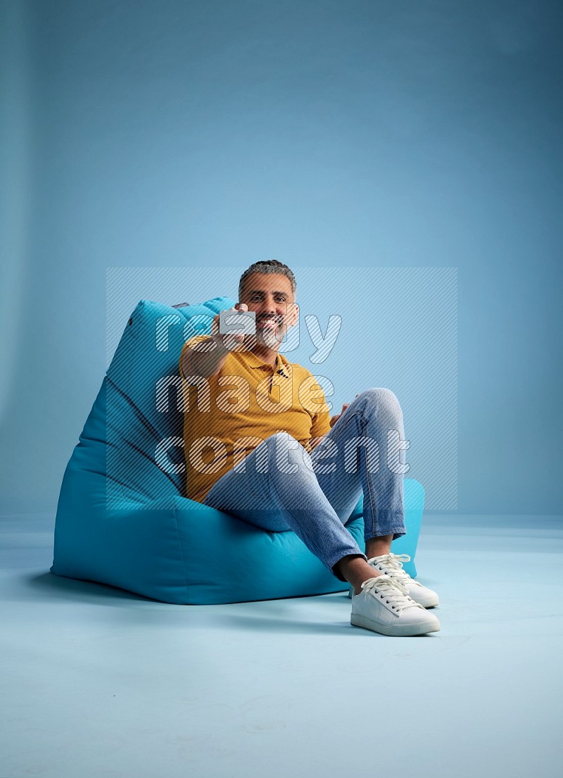 A man sitting on a blue beanbag and holding ATM card