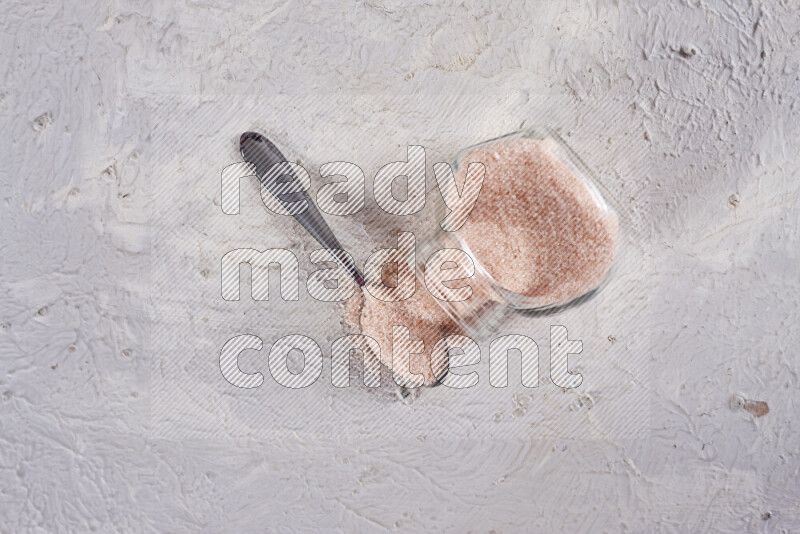 A glass jar full of fine himalayan salt on white background