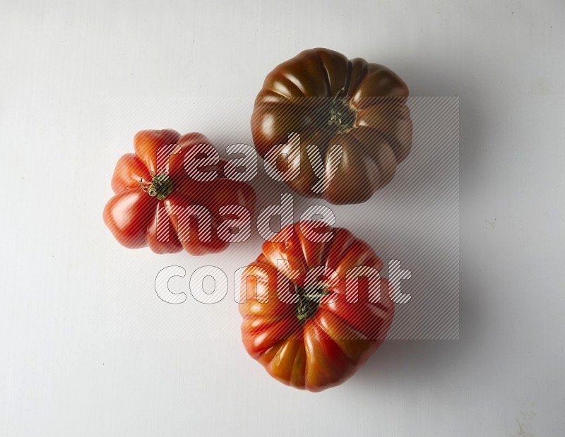 three heirloom tomatoes topview on a white background