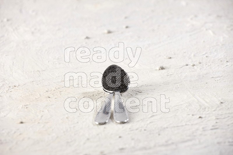 2 metal spoons full of black seeds on textured white flooring in different angles