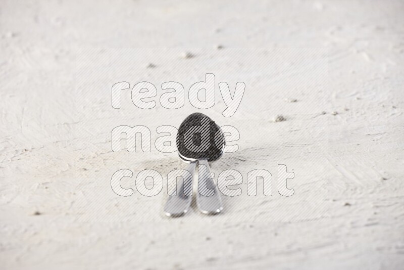 2 metal spoons full of black seeds on textured white flooring