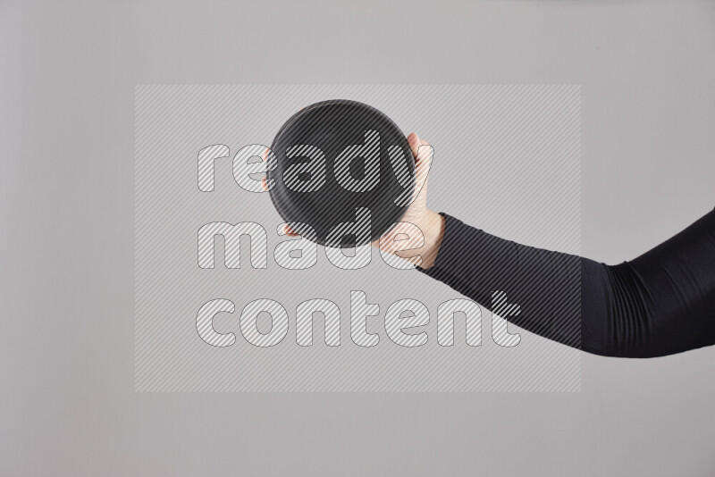 A woman in black abaya holding different pottery essentials in different positions