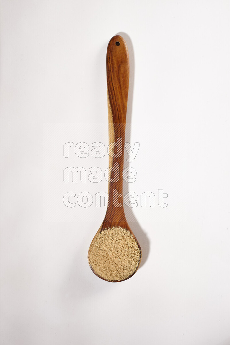 A wooden ladle full of ground ginger powder on white background