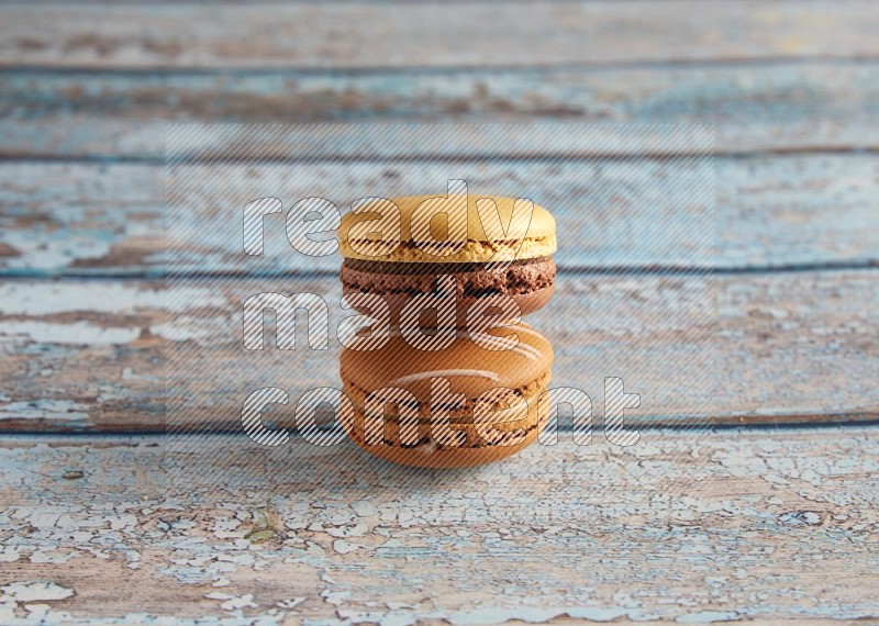 45º Shot of of two assorted Brown Irish Cream, and Yellow, and Brown Chai Latte macarons  on light blue background