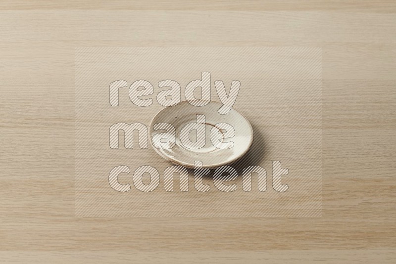 Flat pottery plate coaster on oak wooden flooring, 45 degrees