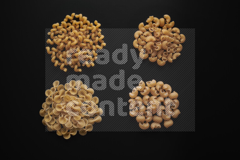 Different pasta types in bunches on black background