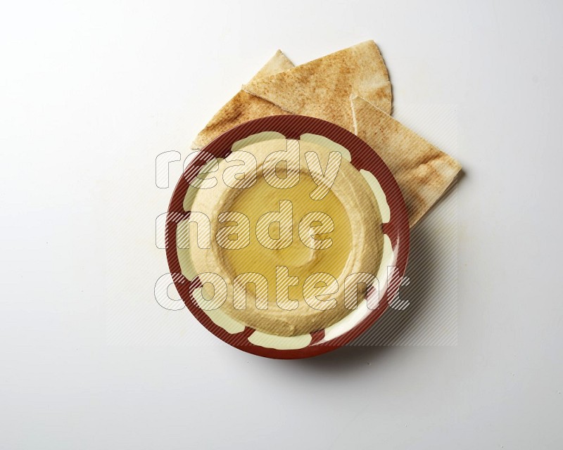 Hummus in a traditional plate garnished with olive oil on a white background