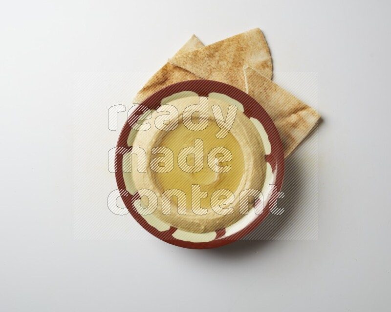 Hummus in a traditional plate garnished with olive oil on a white background