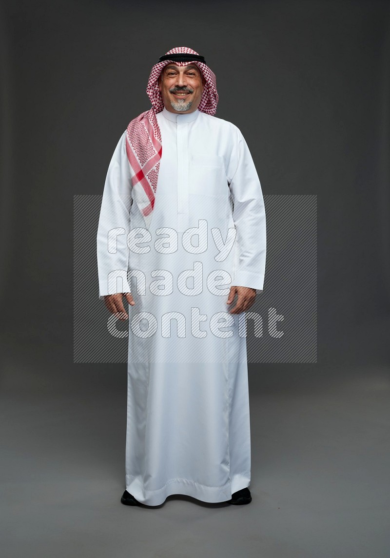 Saudi man with shomag Standing Interacting with the camera on gray background