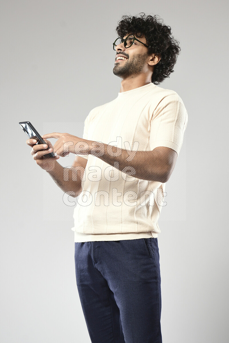 A man wearing casual standing and browsing on the phone on white background